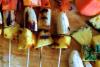 Brochetas de fruta a la parrilla sobre una tabla de madera.