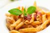 Pasta con tomate adornados con albahaca.