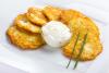 Tortitas de patata en un plato con nata condimentada y cebollino.