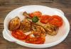 Alcachofas y tomate asados en un plato.