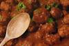 Albóndigas con salsa de tomate y una cuchara de palo.