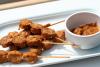 Satay de pollo con salsa de cacahuete para mojar.