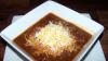 Chile con carne y mole en su plato con queso rallado por encima.