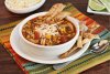 Sopa de pollo y tortilla de maíz en un cuenco.
