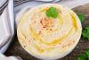 Hummus casero en un cuenco decorado con garbanzos cilantro, grabanzos cocidos y aceite de oliva.