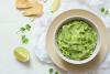 Guacamole en un cuenco con un cuarto de lima y triángulos de maíz.