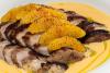 Pechuga de pato aromatizada a la naranja con salsa y gajos de naranja tostados.