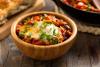 Shakshuka con huevo servida en un bol de madera.