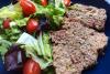Lonchas de molde de carne fiambre con ensalada en un plato de cerámica azul.
