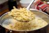 Spaetzle hirviendo en una olla y una rasera con spaetzle recién hervido.