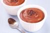 Postre de chocolate en un recipiente blanco con una cuchara al lado.