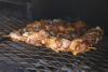 Sosaties de pollo sobre la parrilla de una barbacoa de carbón.