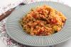 Un plato con bulgur pilaf con tomate, pimiento y tirabeques.