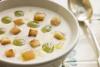 Plato de ajo blanco malagueño con guarnición de pan frito y uvas.