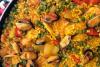 Detalle de un arroz en paella con pescado, anillas de calamar, gambas, mejillones, pimiento y guisantes.