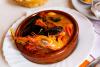 Suquet de pescado con langostinos y mejillones servido en una cazuela de barro.