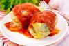 Un plato con hojas de repollo rellenas cubiertas de salsa de tomate.