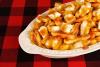 Una fuente con poutine de queso y salsa oscura.