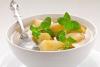 Un cuenco con compota de manzana adornada con hojas de menta.