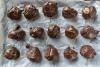 Bolas de mantequilla de cacahuete y chocolate secándose sobre papel parafinado.