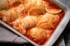 Rollitos de pescado ya cocinados adornados con medias rodajas de limón.
