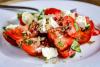 Ensalada de tomate y queso con pangrattato en un plato blanco.