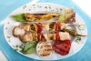 Pinchos de pescado acompañados de lechuga y hortalizas a la plancha.