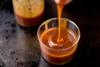 Salsa de caramelo casera cayendo sobre un recipiente de vidrio.