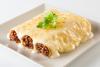 Un palto cuadrado con tres canelones de carne cubiertos de salsa de queso.
