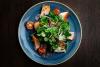 Ensalada de berros, tomates cherry, rábanos, salmón  y semillas  de sésamo en un plato azul.