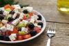 Ensalda griega con tomate, queso feta, pepino, cebolla y aceitunas negras en un plato.