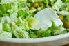 Una ensalada verde con queso y alño de menta en una ensaladera..