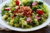 Un plato de ensalada de escarola con pollo y tomatitos.