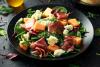 Un plato con ensalada de melón con jamón de Parma y queso mozzarella.