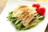 Pollo bang bang en un plato cuadrado, acompañado de tomates.