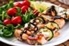 Brochetas de rape, salmón y langostinos acompañadas de ensalada.