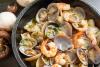 Sartenada de champiñones, almejas y langostinos, generada por IA.
