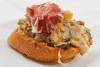 Pincho de revuelto de setas decorado con una loncha de jamón serrano.
