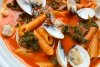 Detalle de una sopa de tomate y pasta con almejas y col rizada.