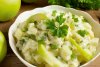 Una ensaladera con ensalada irlandesa de patata y manzana.