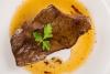 Un filete de hígado bañado con su salsa y decorado con unas hojas de perejil.