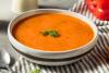 Un plato hondo con sopa de pimientos morrones.