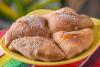 Sopapillas doradas y esponjosas servidas en un plato amarillo, espolvoreadas con azúcar glas y rociadas con miel.