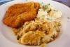 Un plato con un filete de cerdo empanado acompañado con repollo encurtido y puré de patata, al estilo polaco.