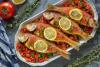 Salmonetes al horno servidos sobre una cama de tomate concasé y decorados con rodajas de limón y hierbas frescas.