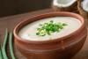 Un cuenco con sopa de crema de coco decorada con cebollino picado.