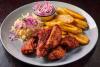 Un plato de pollo con tajadas acompañado de ensalada de repollo y cebolla encurtida.