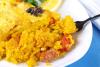 Un plato con una porción de arroz con costra acompañado de limón y perejil fresco.