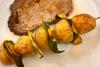 Una brocheta de patata con lima como acompañamiento de un filete a la plancha.