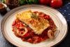 Un plato de bacalao al horno con salsa de tomate y pimiento.